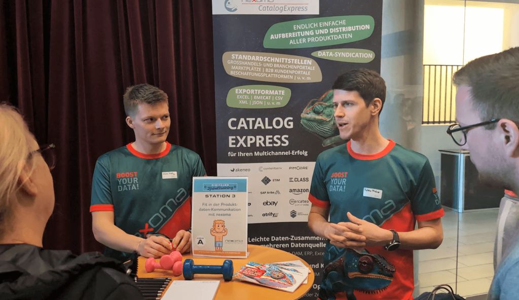 Beitragsbild Digitales Zirkeltraining - Fabian und Kevin beraten Teilnehmer am Stand